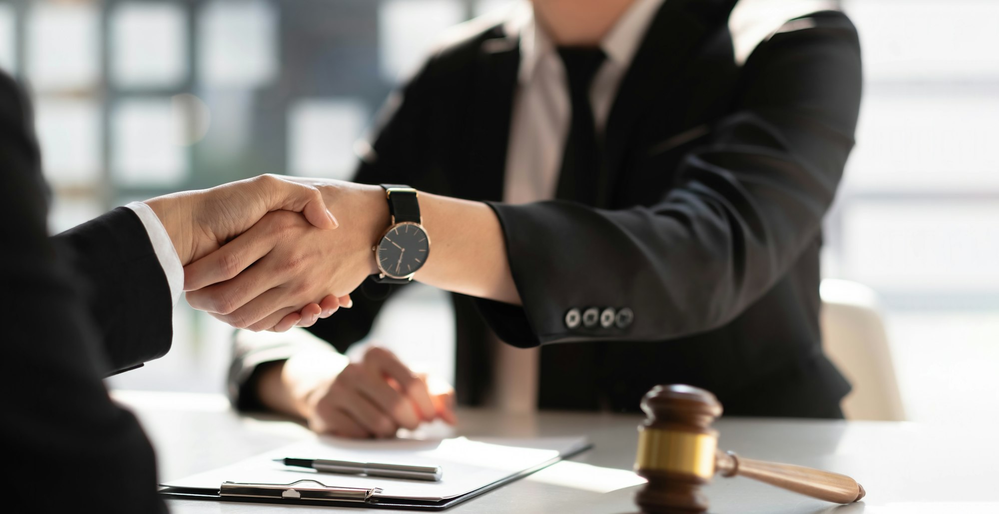 Businessman shaking hands to seal a deal with his partner lawyers or attorneys discussing a contract